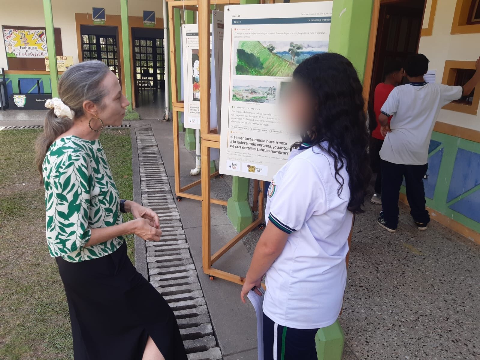 Mediación de la artista con una participante frente a las láminas de la exposición en la I.E. Boquía
